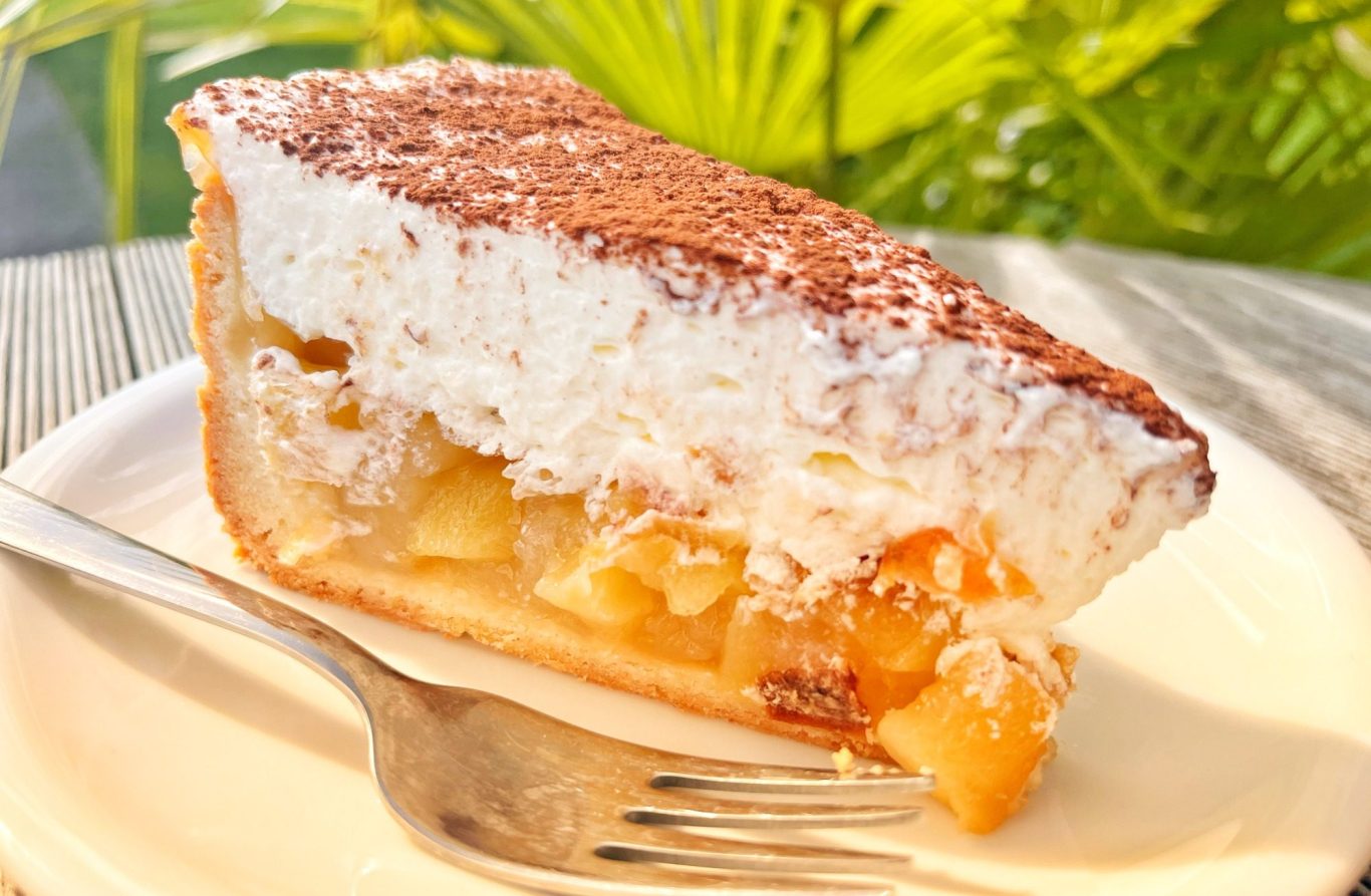 Café Apfelweinkuchen mit Sahnehaube und Kakao-Pulver bestäubt.